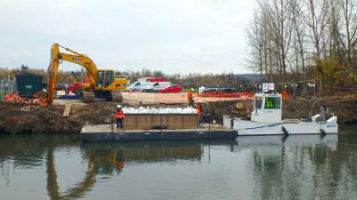 A l’aide de pelles sur ponton :  manutention des fûts de produits pétroliers en sacs étanches, transport fluvial jusqu’à la zone de reprise